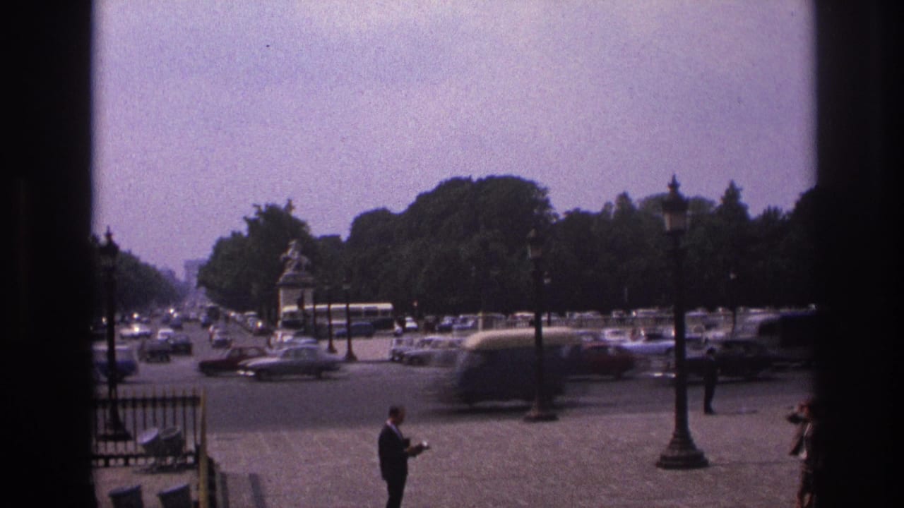 Elevated view of a Paris square with cars, pedestrians, trees, lamp posts, and a central monument.