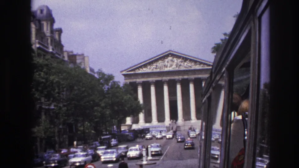 1967 Paris traffic scene facing the Panthéon, with classic cars, pedestrians, tree-lined sidewalks, and a vehicle side in frame.
