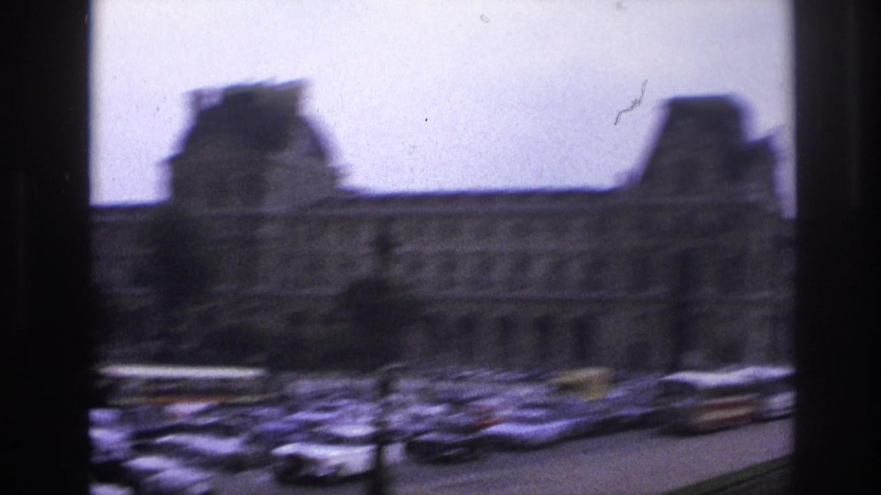 Panning view of a long historic facade with dense cars in the foreground.