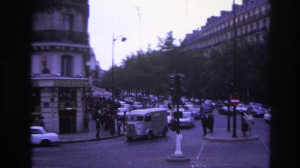 1967 Paris 8mm frame showing a Citroen-style delivery van, cars, pedestrians, traffic lights, and tree-lined street edges.