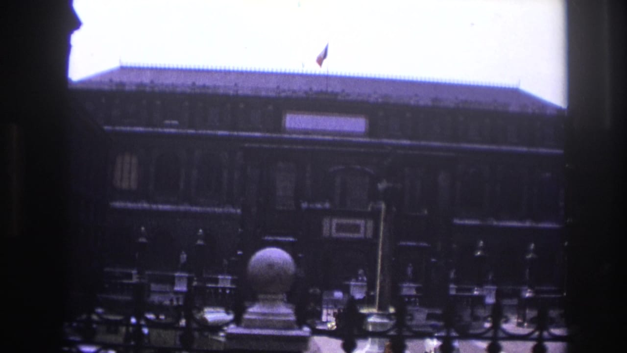 Courtyard facade with dark framing, ironwork, roof flag, and stone ornament.