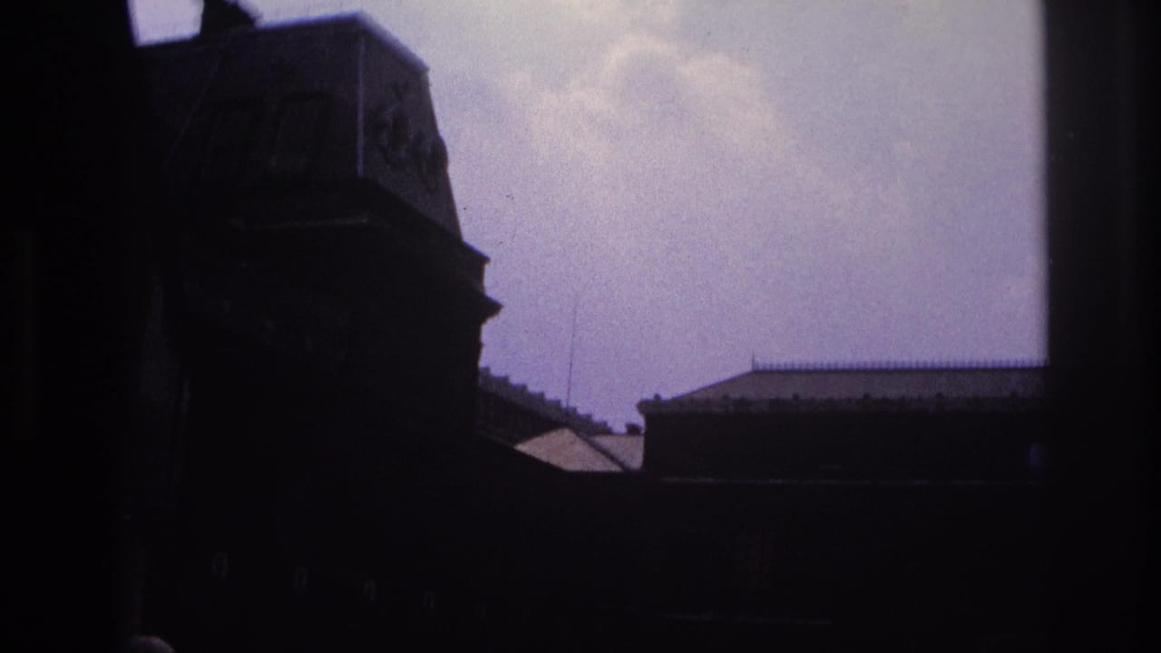 1967 Paris 8mm frame with shadowed building forms and rooftops seen from a moving sightseeing bus.