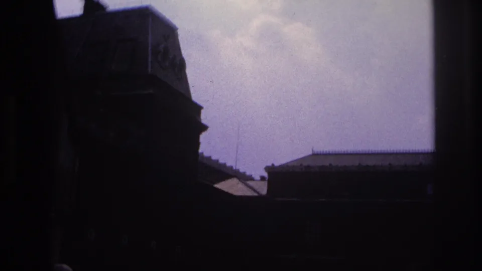 1967 Paris 8mm frame with shadowed building forms and rooftops seen from a moving sightseeing bus.