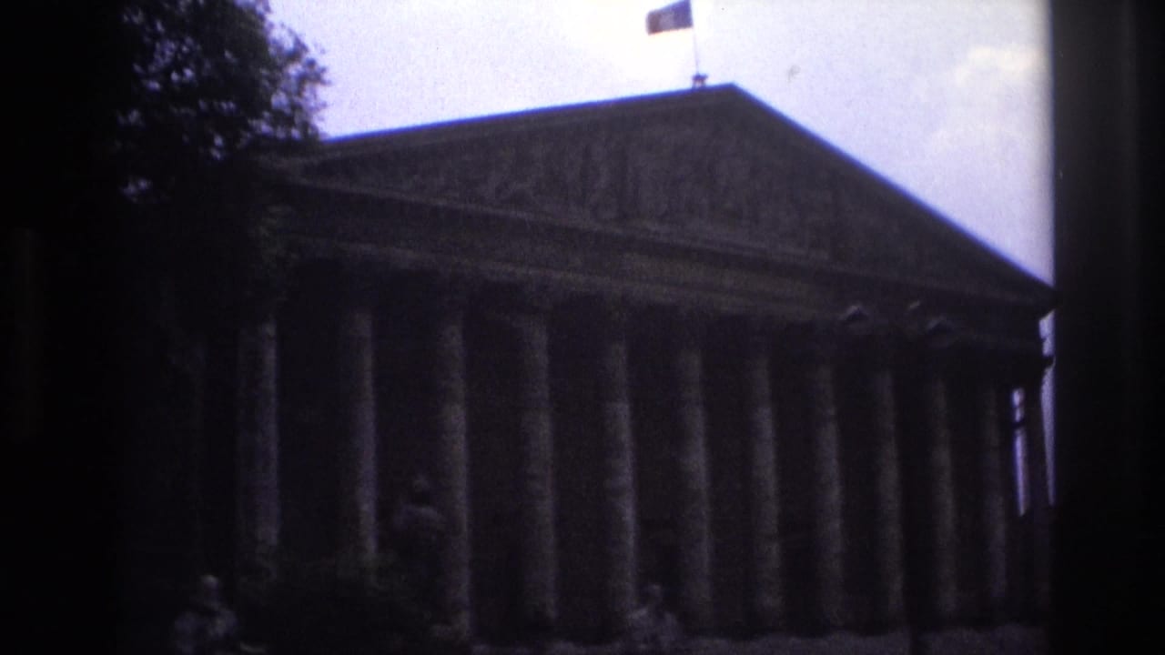 Dark view of a classical building with columns and a flag.