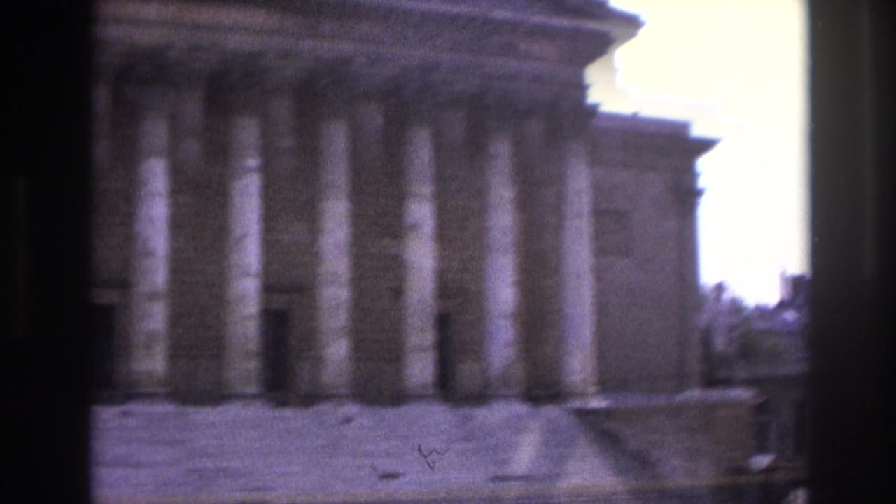 Neoclassical building facade with columns and dark foreground obstruction.