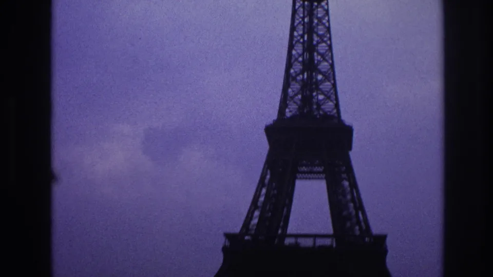 1967 Paris frame with part of the Eiffel Tower seen through dark film-frame edges against a cloudy sky.