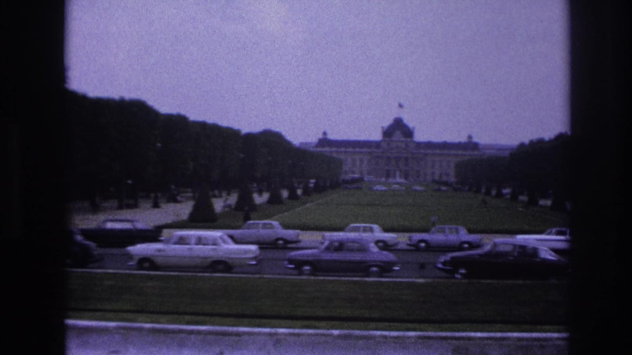 1967 Paris view toward a grand palace-like building across formal lawns and tree-lined traffic lanes with mid-century automobiles.