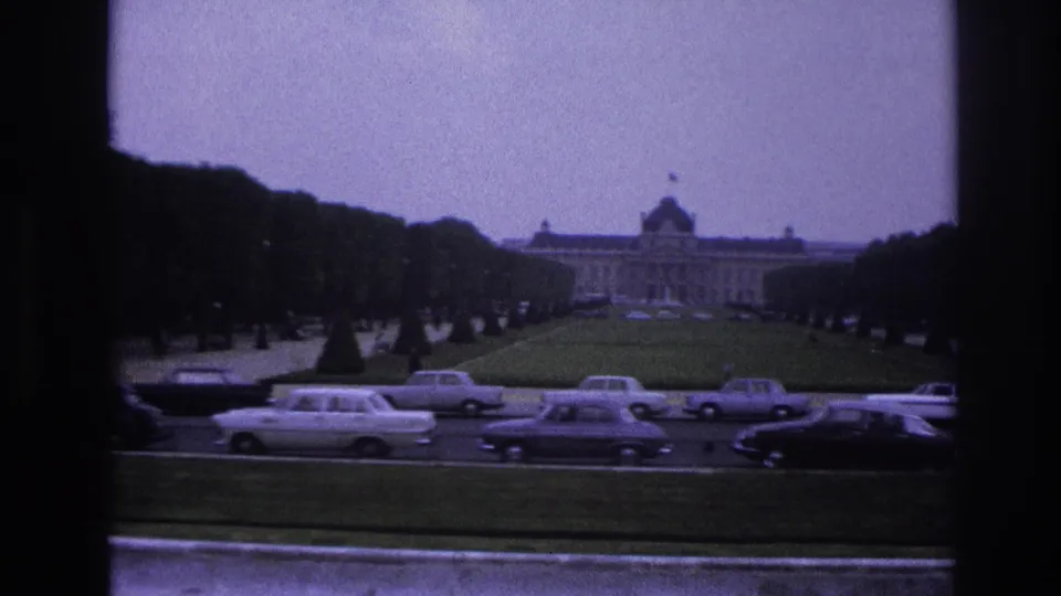 1967 Paris view toward a grand palace-like building across formal lawns and tree-lined traffic lanes with mid-century automobiles.