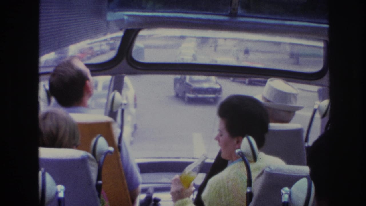 Tour bus passengers face forward as cars pass outside the front windows.
