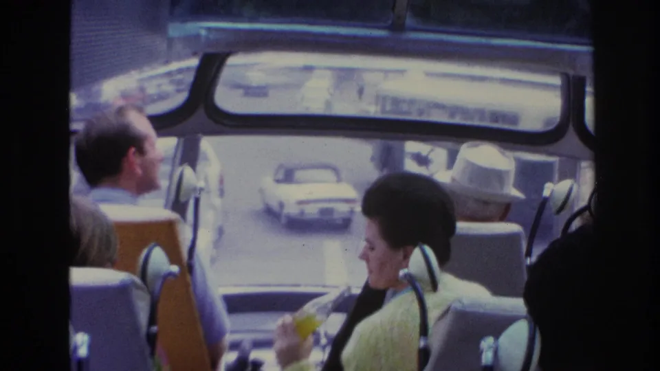 1967 Paris travel footage looking through a tour vehicle interior toward street traffic and seated passengers.