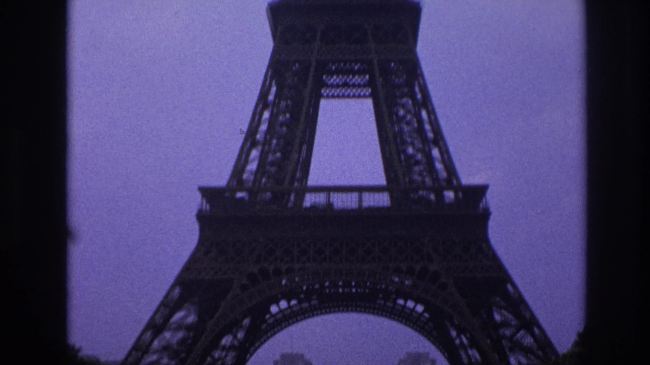 Closer view of the Eiffel Tower lower structure framed by dark vertical edges against a muted sky.