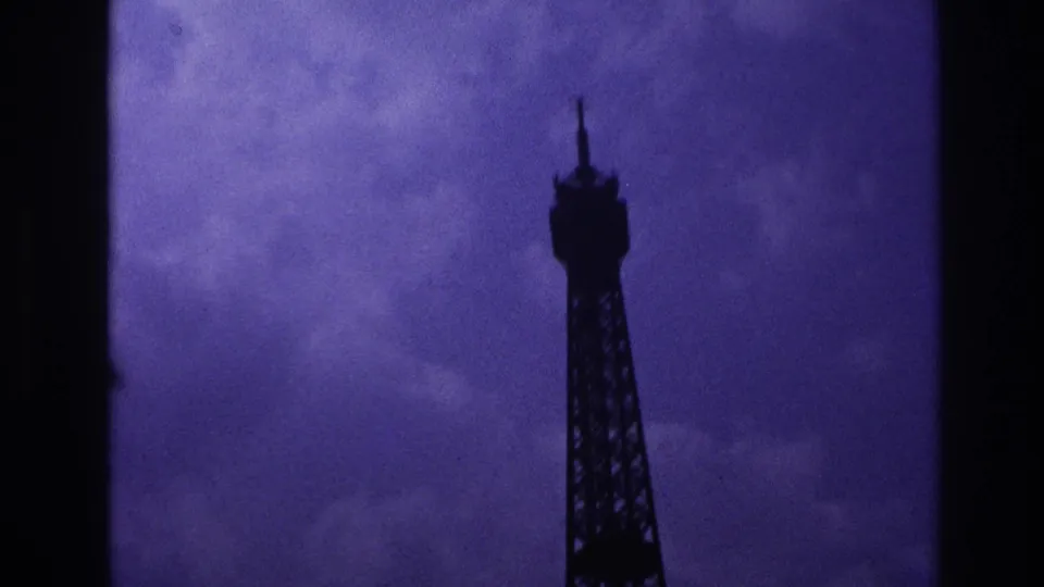 1967 Paris 8mm frame showing the Eiffel Tower upper section shifted right against a soft grey-purple cloud backdrop.