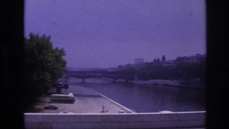 1967 Paris view from the bus toward the Seine, with riverside trees, embankment, and a stone bridge beyond.