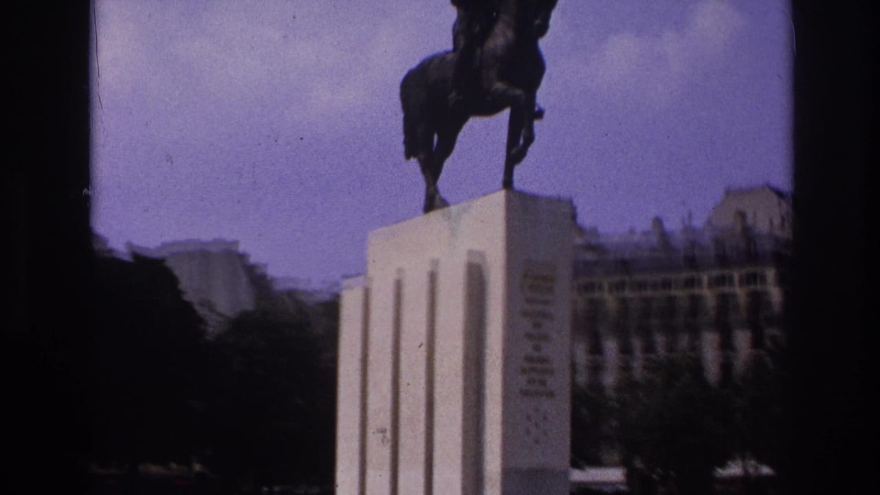 Paris travel-film frame with a closer handheld view of the equestrian monument silhouetted above a pale pedestal.