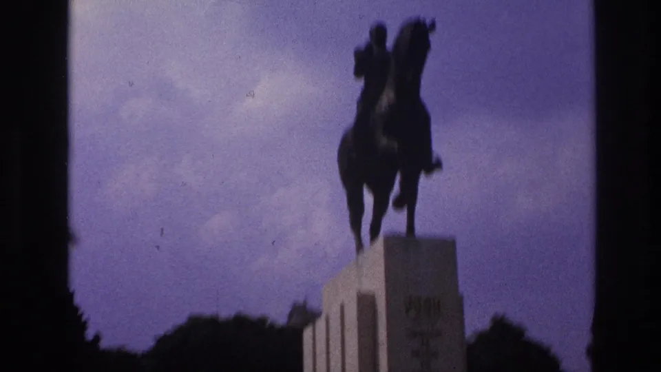Low-angle 1967 Paris frame showing the equestrian statue silhouetted over the pedestal with trees below.