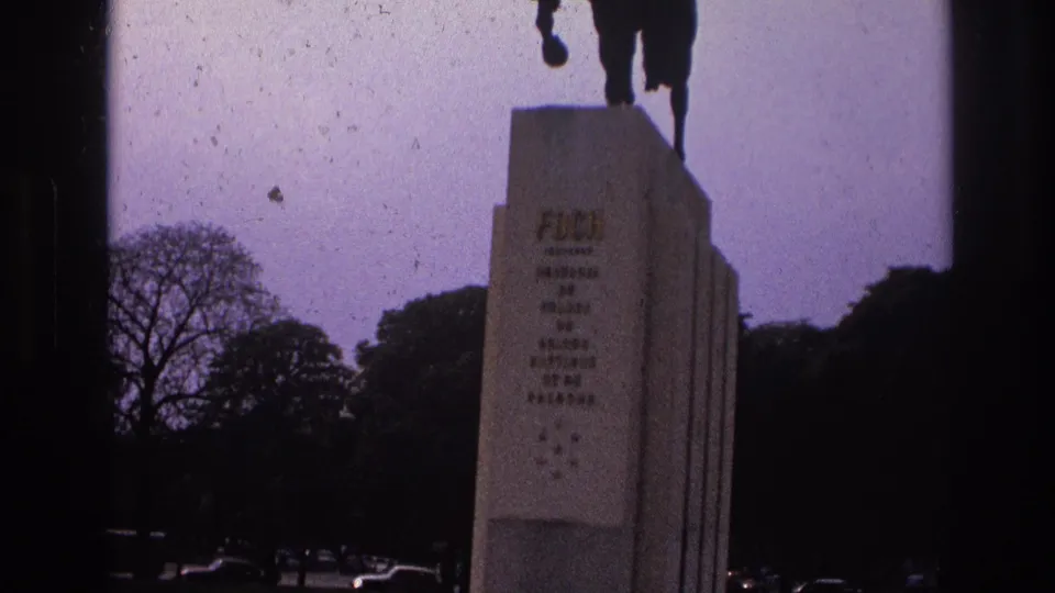 1967 Paris frame centered on the monument pedestal and partial horse statue, with park trees and cars behind.
