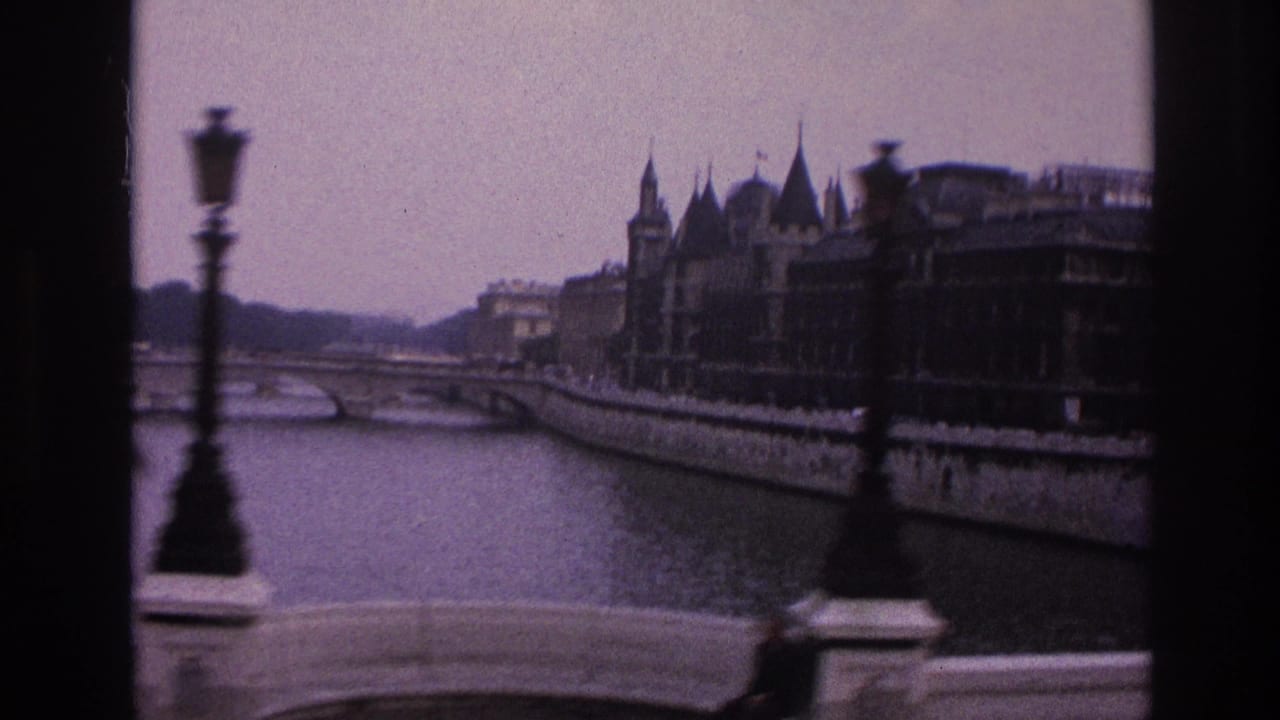 Seine riverside view with a street lamp, bridge railing, ornate buildings, and a red blurred vehicle detail.