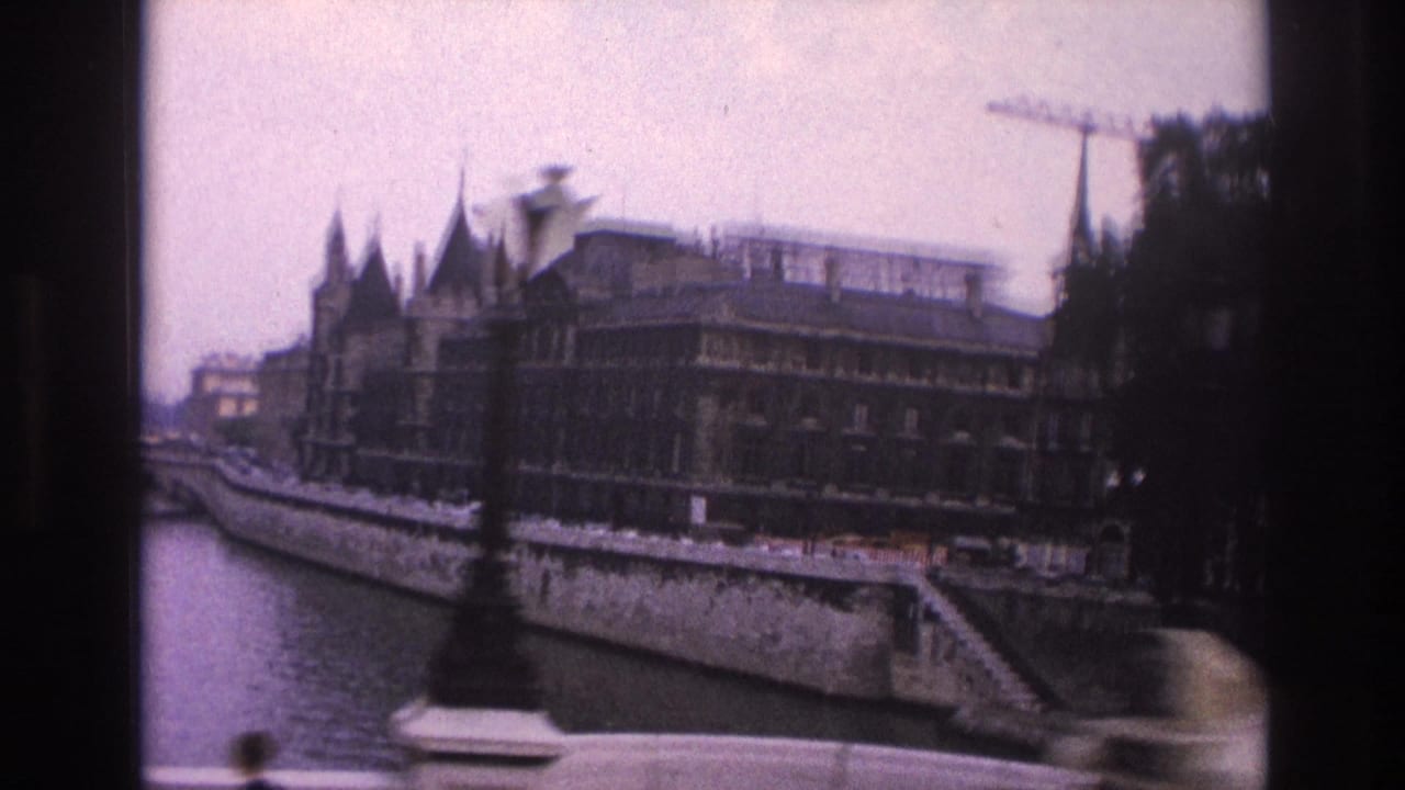 Seine riverfront with stone embankment, moored boat, ornate buildings, trees, and a crane.