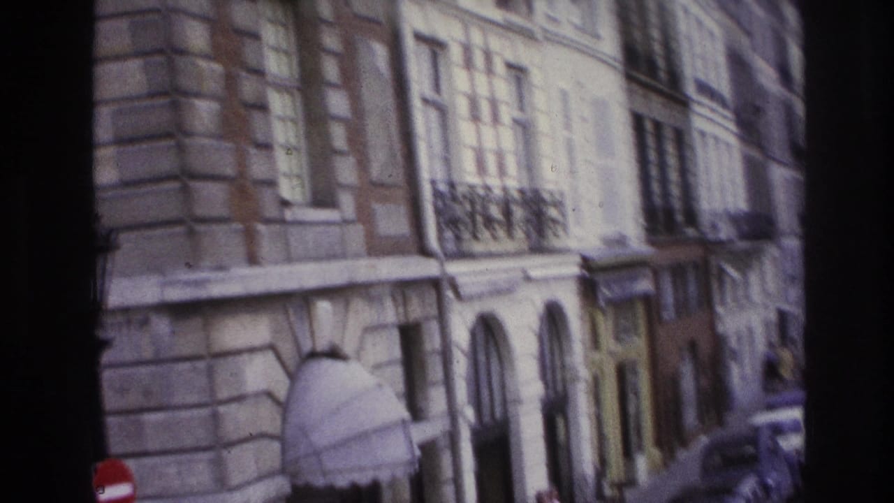 Stone building facade with tall windows, arched entry, sidewalk, and traffic signs.