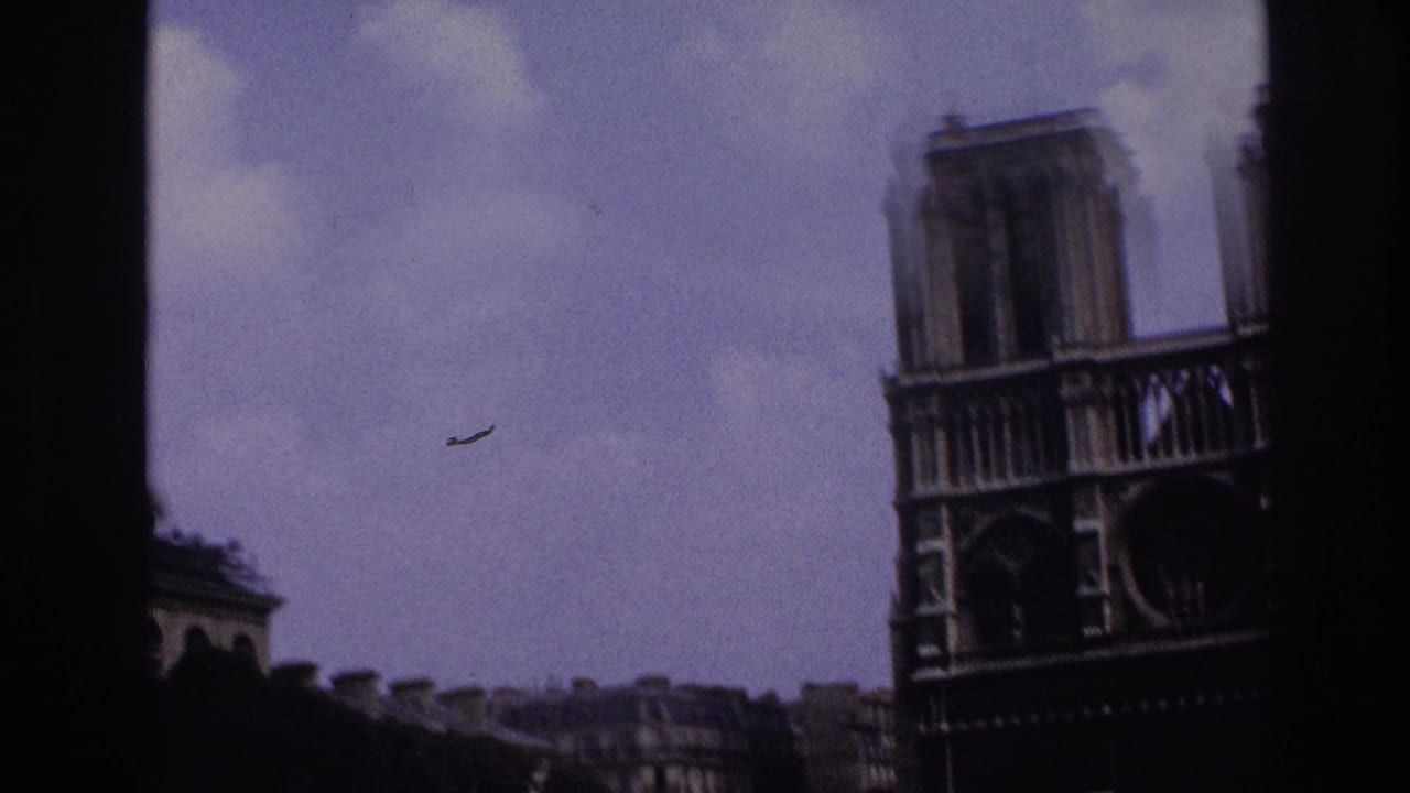 1967 Paris home-movie frame showing Notre-Dame Cathedral's facade from a moving vehicle, with soft focus and dark frame edges.