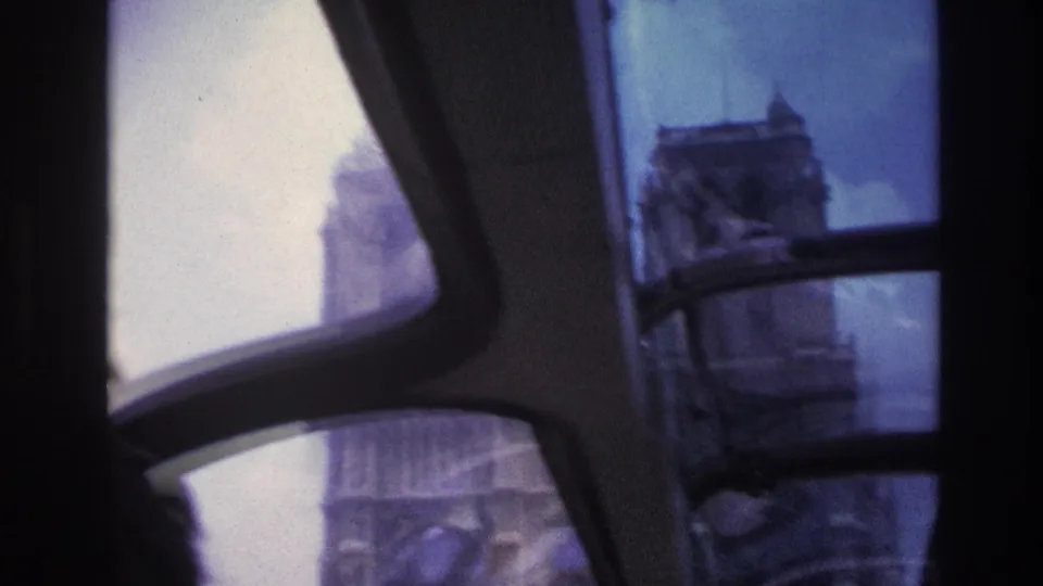 A final 1967 Paris vehicle-window view catches part of Notre-Dame, softened by motion blur, glass reflection, and dark interior trim.