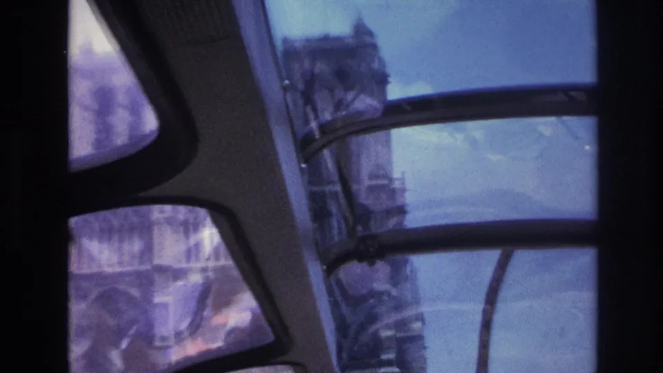 1967 Paris view through curved tour-bus windows, with blurred buildings and tinted glass dominating the frame.