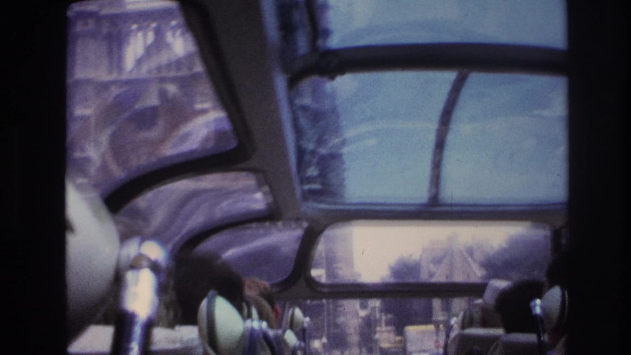 Interior tour-bus view in Paris with curved windows, partial passengers, and a blurred street scene visible through the glass.