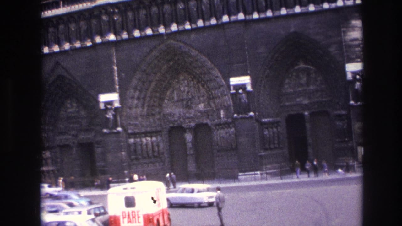 1967 Paris street view with parked cars, pedestrians, and a Gothic cathedral facade behind a red and white van.