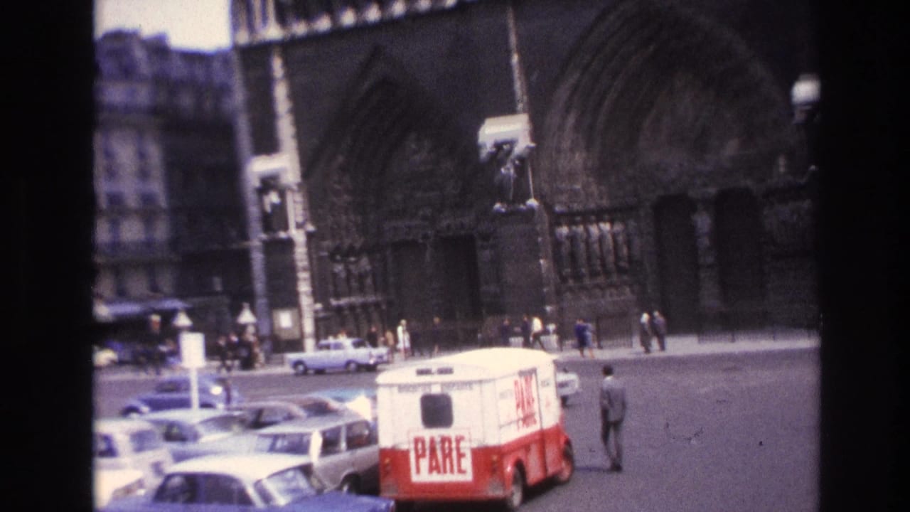 Parking area and pedestrians in front of a large Gothic cathedral.