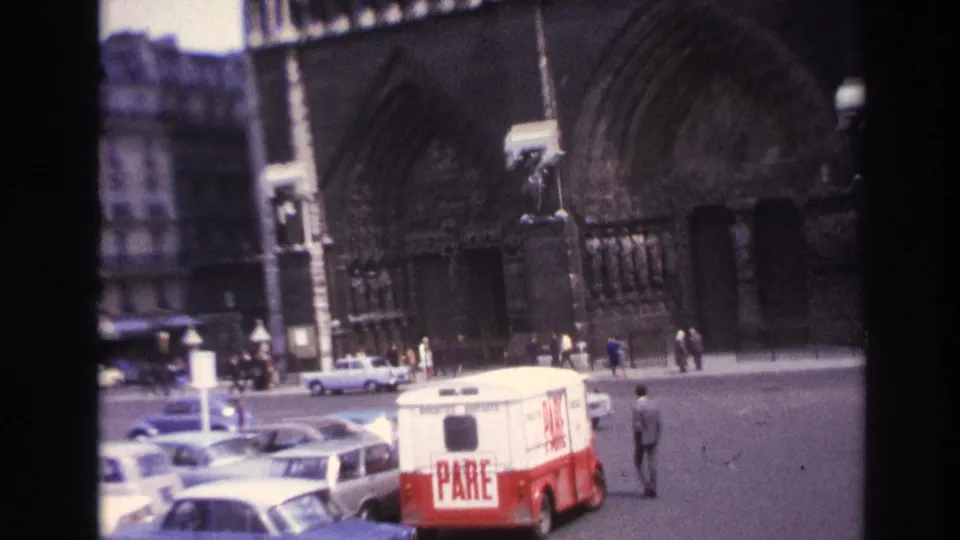 1967 Paris street scene showing a Gothic cathedral entrance, vintage cars, pedestrians, and a van marked PARE.