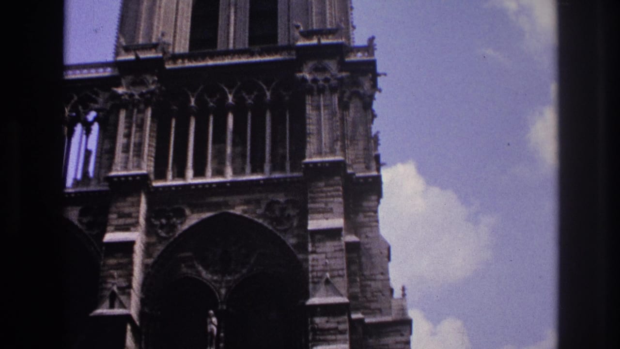 1967 Paris Super 8 frame showing part of a Gothic cathedral facade, with pointed arches, carved stone details, and dark framing at the edges.