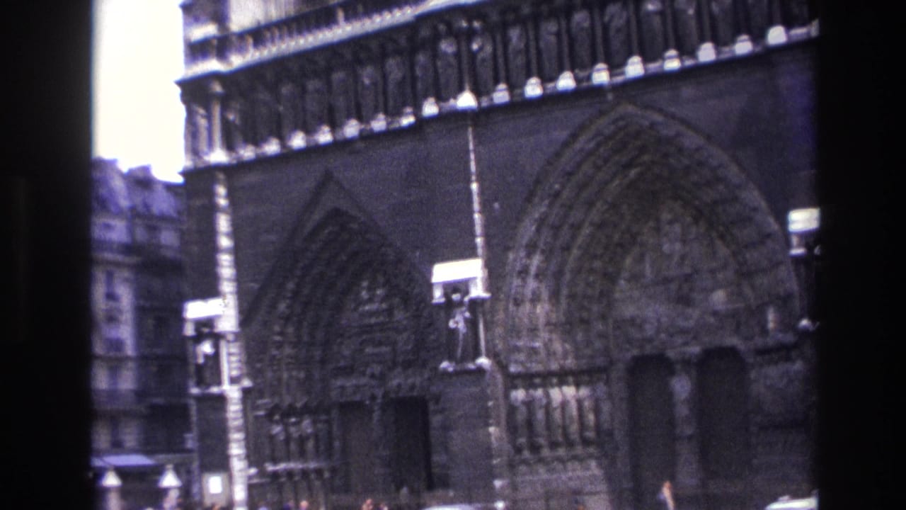 1967 Paris home-movie frame showing Notre-Dame Cathedral portals, carved arches and a dark vertical frame edge.