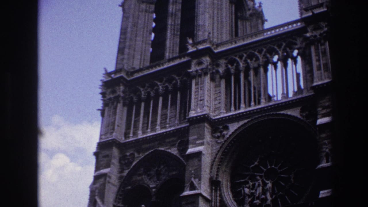 1967 Paris home-movie frame showing a low-angle Notre-Dame Cathedral facade with stone tracery, towers, and dark film gate edges.