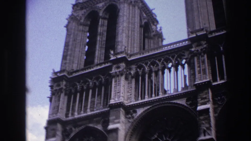 1967 Paris frame with a close, low-angle view of Notre-Dame's Gothic stone facade, including tracery, columns, and upper tower details.