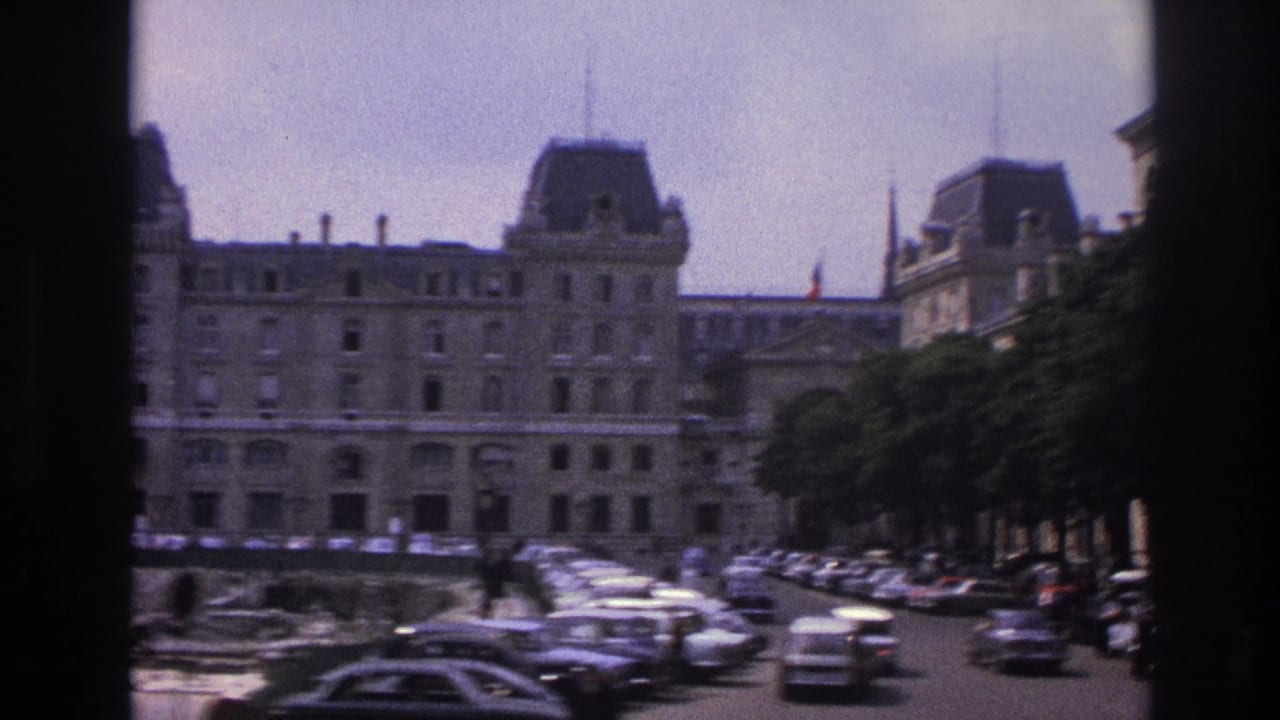 1967 Paris street view of a large historic stone building, rows of cars, and dark vertical window framing.