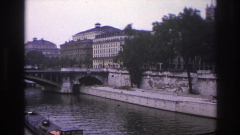Late frame of the 1967 Paris river view, with the barge partly cropped at lower left and the Seine embankment, bridge, trees, and buildings visible.