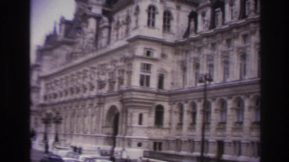 Closer 1967 home-movie view of an ornate Paris facade with arched windows, carved stonework, and a mansard roofline.