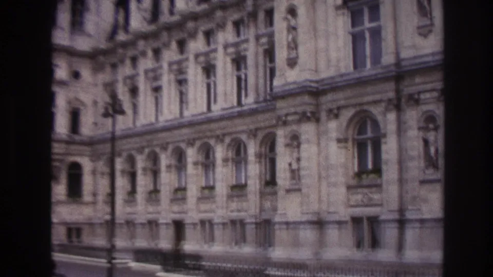 1967 Paris frame showing an ornate stone facade with arched windows, sculptural niches, railing, and a street lamp.
