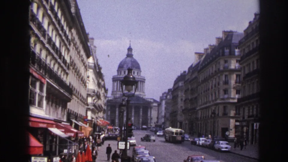 1967 Paris street view toward a domed building, with pedestrians, buses, parked cars, awnings, and Haussmann-style facades.