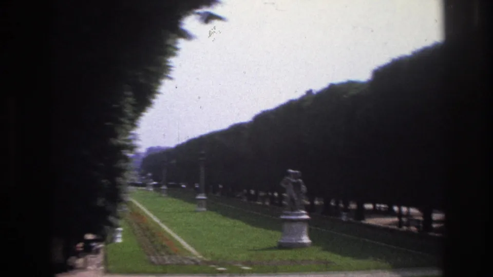 1967 Paris garden view with a long hedge-lined allée, clipped lawn, walkway, and a statue positioned along the axis.