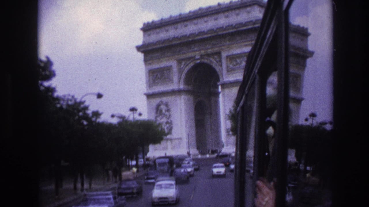Arc de Triomphe framed by a vehicle window with cars approaching below.