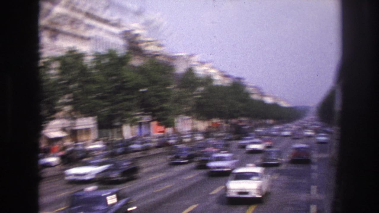1967 Paris street view from a bus, showing traffic on a broad tree-lined boulevard with pale apartment buildings.