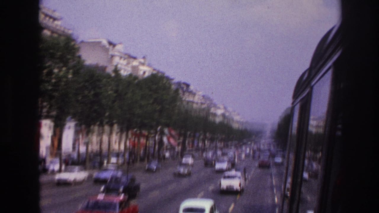1967 Paris boulevard traffic viewed through a bus window, with rows of trees, apartment buildings, and cars moving along multiple lanes.