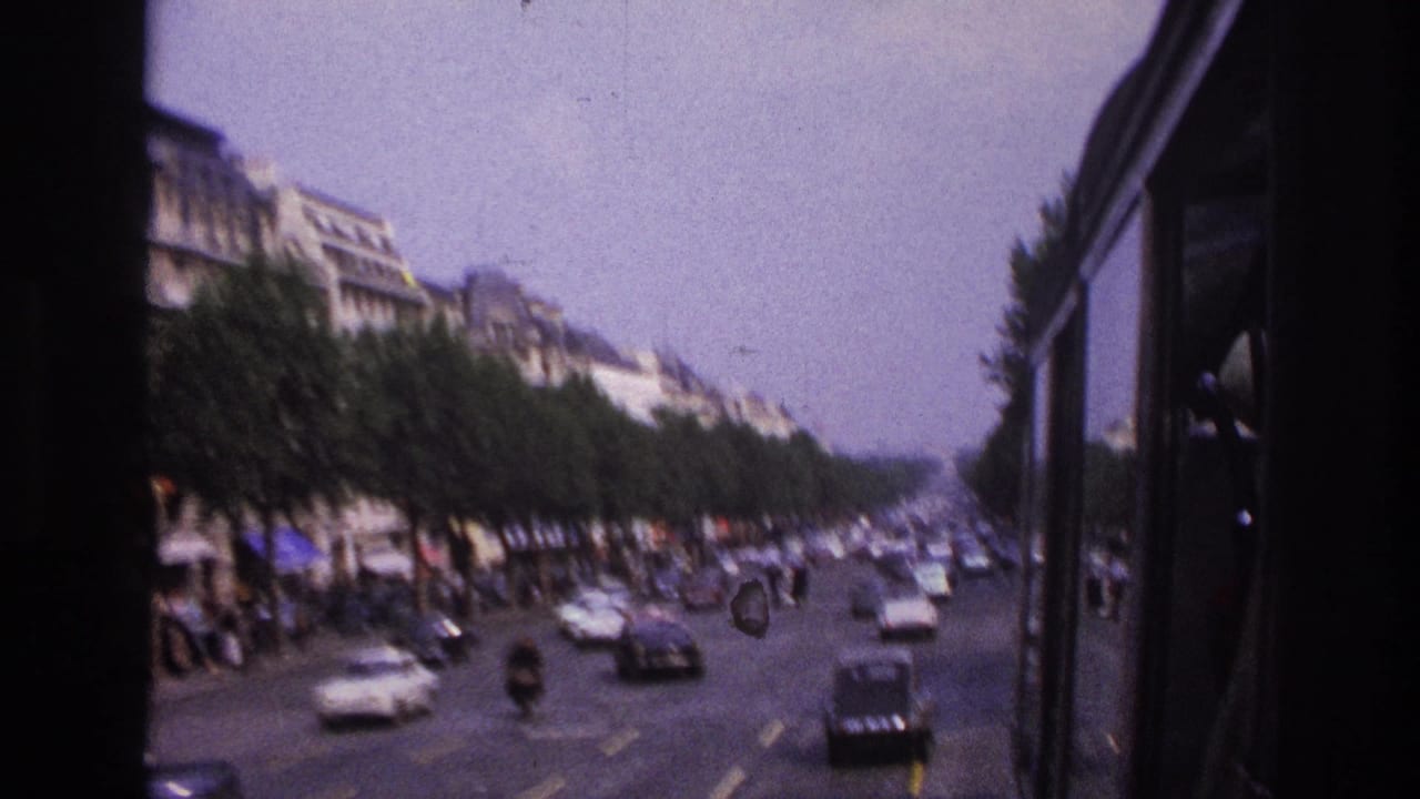 1967 Paris bus-window view looking along a tree-lined roadway with period cars, pedestrians, and soft home-movie blur.