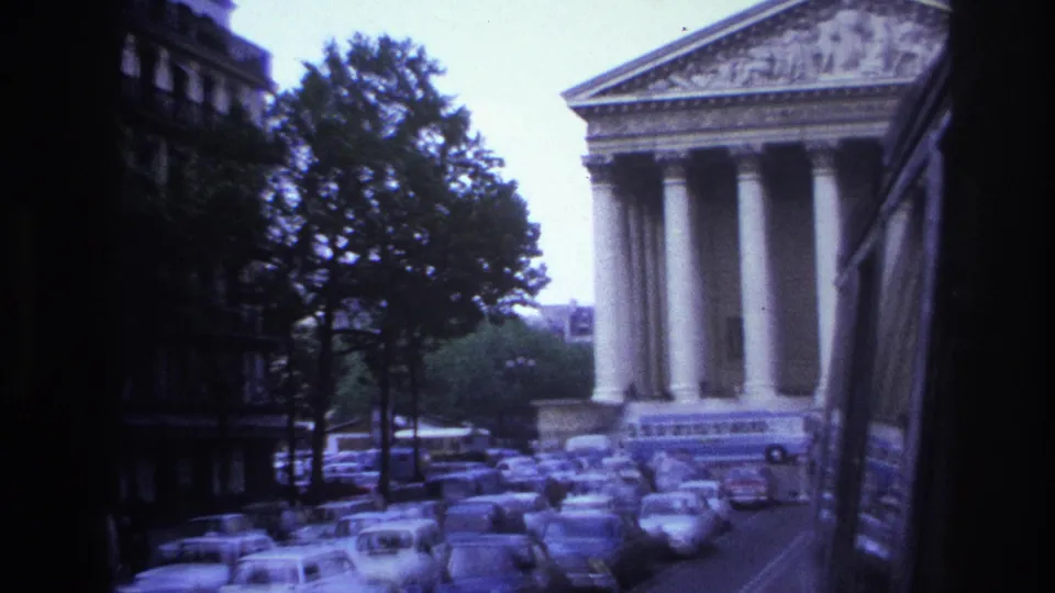 1967 Paris frame from a moving vehicle, showing a closer angle on the neoclassical columns and the crowded curbside parking.