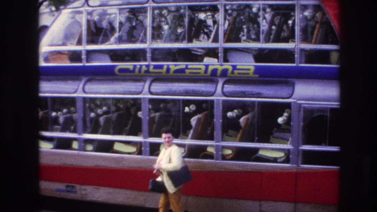 1967 Paris home-movie frame showing a woman in a yellow sweater passing a Citirama double-decker tour bus with passengers visible inside.