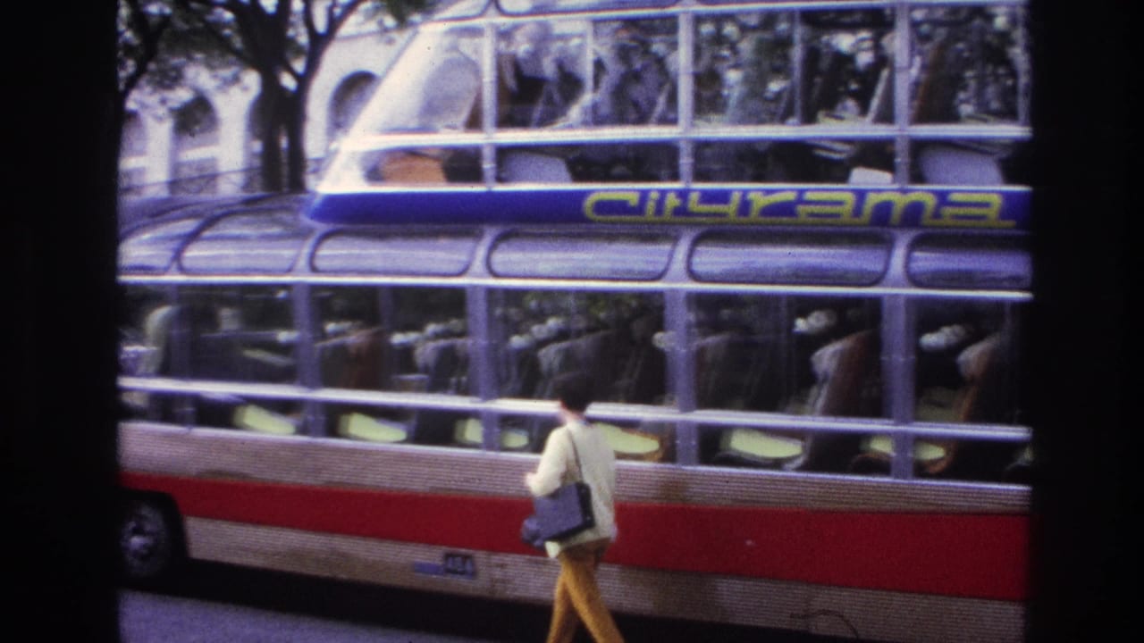 Woman with shoulder bag passes the side of a Citirama bus with passengers at the windows.