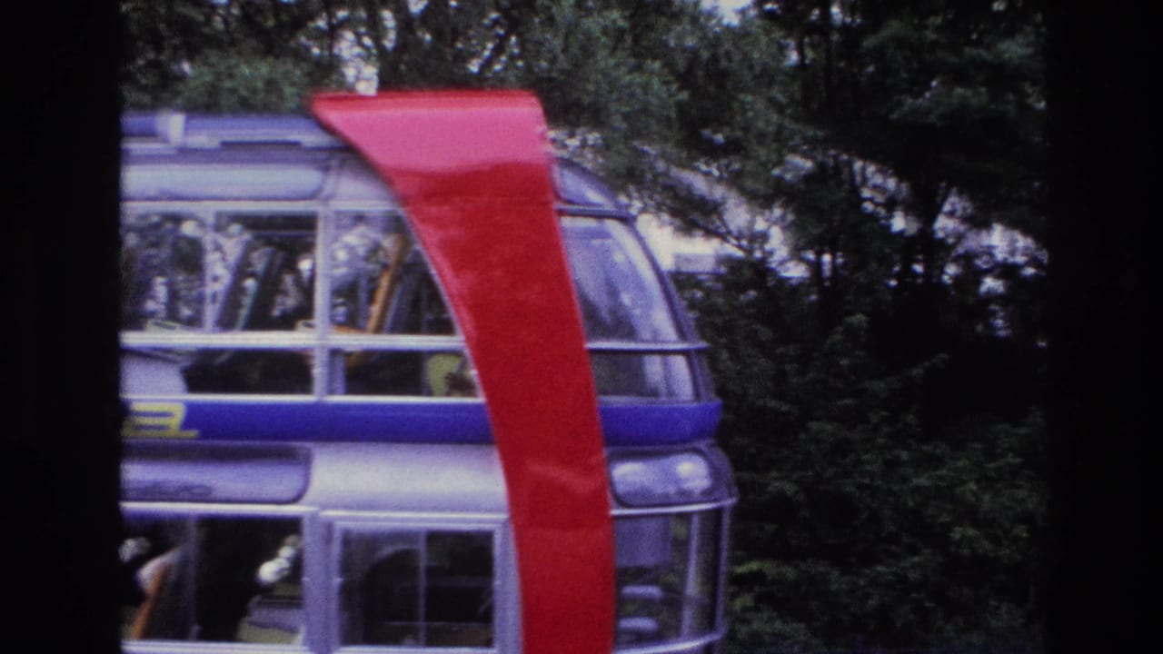 Glass-sided structure with red curved support and trees in the background.