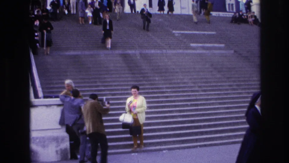 1967 Paris home-movie frame of people gathered near the lower staircase, with pedestrians moving in the background.