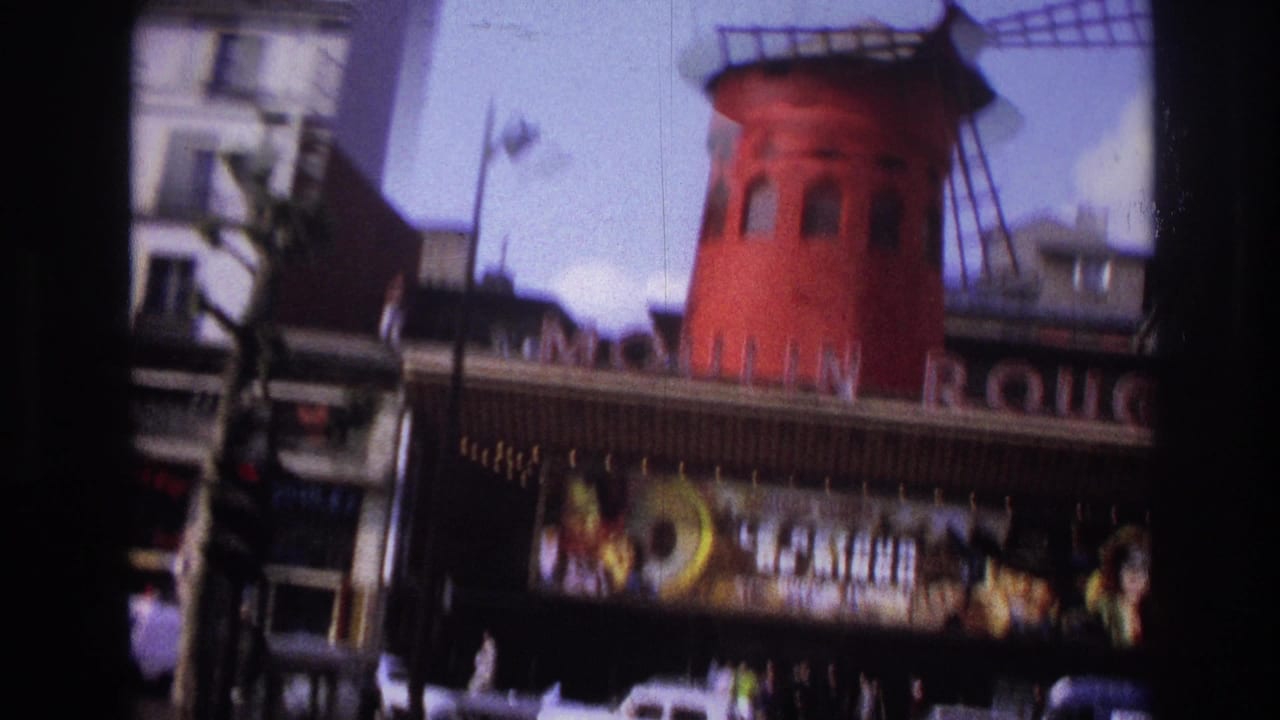 1967 Paris home-movie frame showing the Moulin Rouge red windmill above the marquee with cars and pedestrians below.